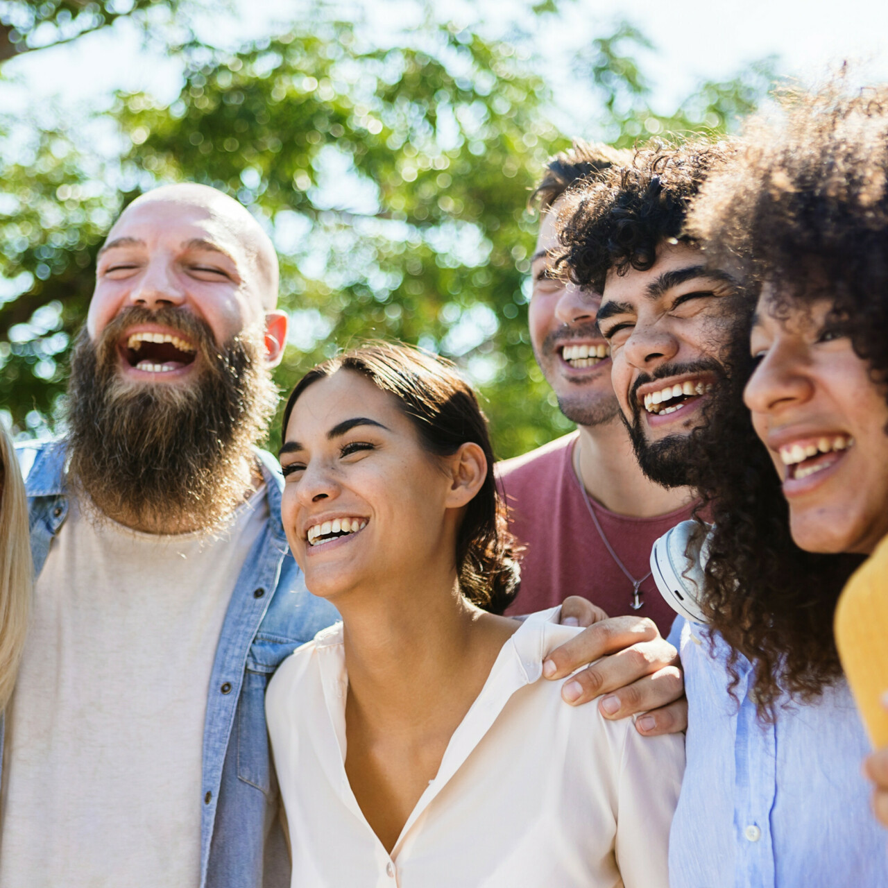 Young group of diverse friends having fun outdoors in a sunny day